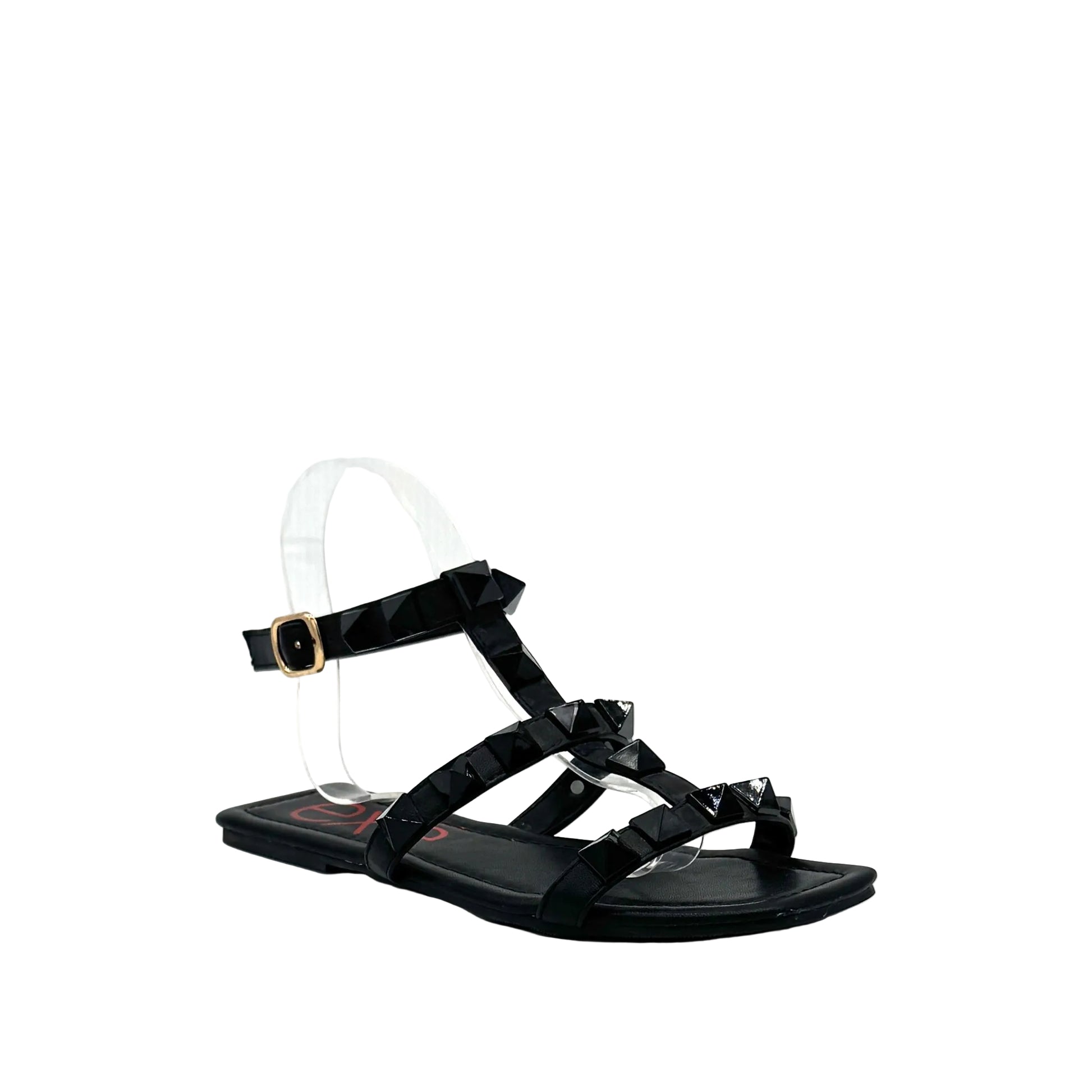 Black: EXE 2269-2781 pyramid stud T-strap flat sandal in black with gold-tone ankle buckle and square toe, side view