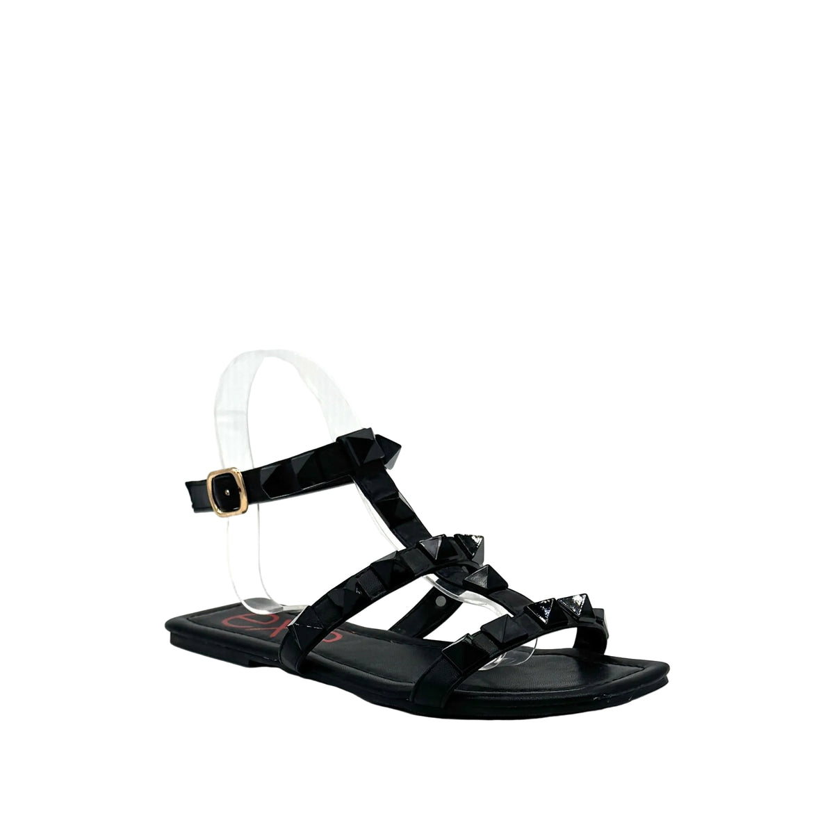 Black: EXE 2269-2781 pyramid stud T-strap flat sandal in black with gold-tone ankle buckle and square toe, side view