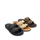 Three women's slide sandals arranged on a white background, each with a large decorative oval buckle embellished with rhinestones. The sandals come in black, tan/beige, and dark brown espadrille-style uppers with braided trim.