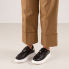 Renato Garini Butterfly black jeweled platform sneakers worn with cuffed tan trousers, showing butterfly and jewel lace accents