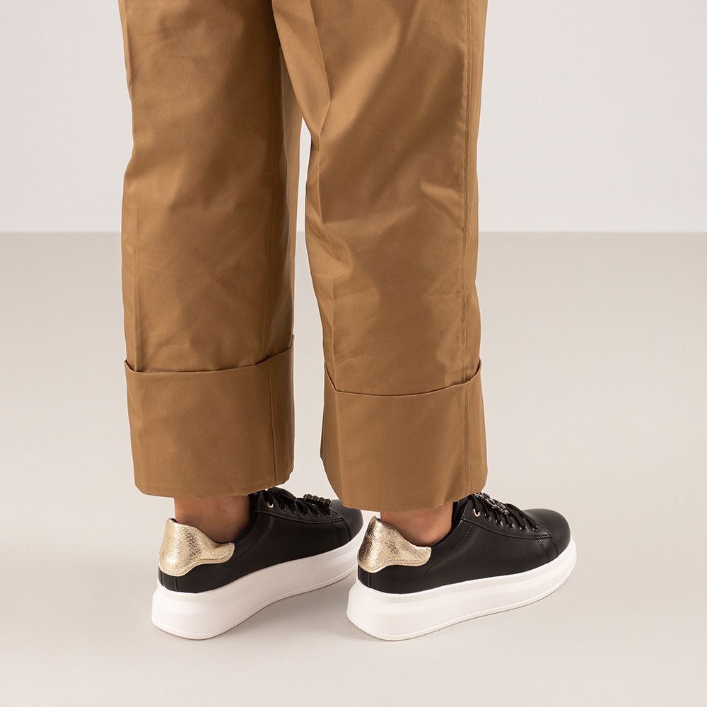 Renato Garini Butterfly black platform sneakers styled with cuffed tan trousers, showing gold-tone heel panels and white soles from behind