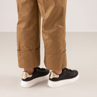 Renato Garini Butterfly black platform sneakers styled with cuffed tan trousers, showing gold-tone heel panels and white soles from behind