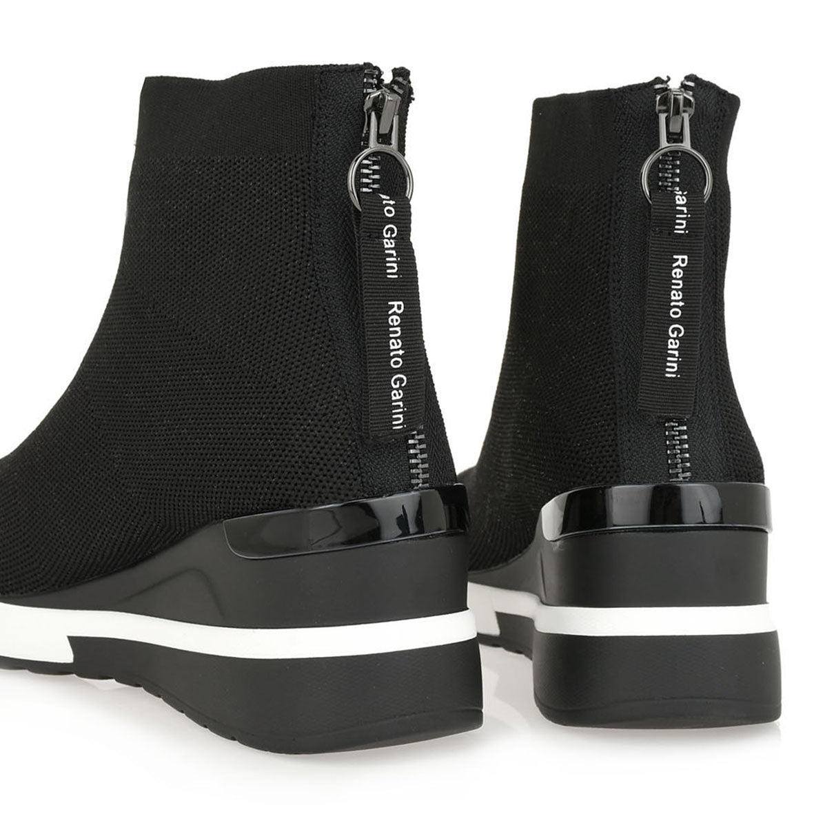 Rear detail of Renato Garini 34-210 black ankle boots with black branded zipper pulls, glossy heel trim and contrasting white stripes on the wedge soles